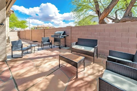 Sunny patio with grill, wicker seating, and private walled yard