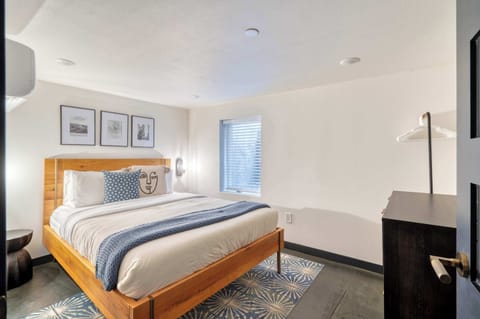 Bedroom with a wooden bed frame, bedside lights, and a blue throw.