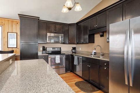 Modern kitchen w/ granite counters, dark cabinetry & stainless steel appliances.