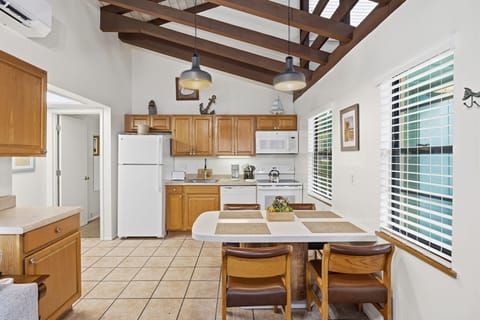 The open kitchen includes wood cabinetry, modern appliances, and a dining table with seating for shared meals.