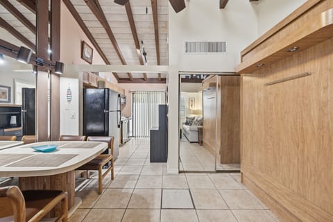An open studio layout features exposed beams, tiled floors, and a functional kitchen setup for comfortable beachfront living.