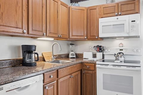 A bright living space features a sofa, flat-screen TV, and coastal-inspired decor for relaxing after a day at the beach.
