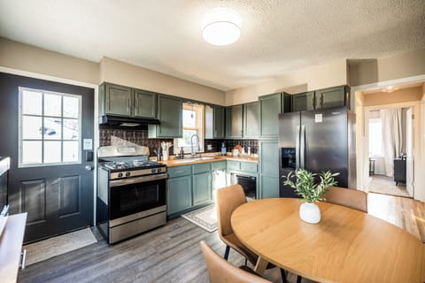 The eat in dining table, perfect for gathering and enjoying meals. You’ll also see the large refrigerator with plenty of room for your groceries and a stairwell leading down to the cozy family room. 