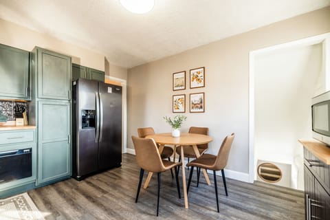 This kitchen corner features an eat-in dining table, perfect for meals, and a large refrigerator for your groceries. A stairwell leads to the cozy family room, with an open layout that ensures a seamless flow, ideal for family and friends to connect.