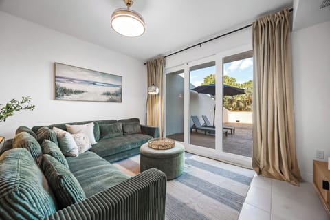 Relax in the modern living room with a green corduroy sectional and access to a private outdoor patio.