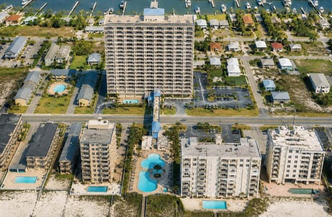 Full aerial view of Crystal Tower with two outdoor pool areas, the Gulf-side lazy river, beach access, and Little Lagoon behind the building.