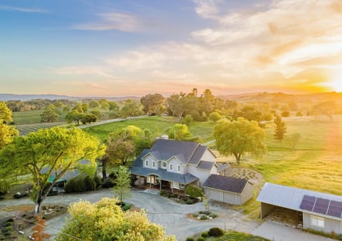 Experience the ultimate in rural luxury with this stunning country home, nestled among rolling green hills and sprawling vineyards. The expansive property features a grand main house with a wraparound porch, a large garage, and solar-equipped outbuildings.