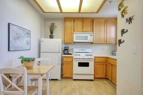 This cozy kitchen features warm wood cabinetry, a full-size refrigerator, gas stove, microwave, and a quaint dining nook, perfect for enjoying meals in a bright, inviting space.