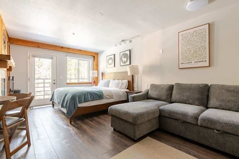 Modern studio with king bed, sofa, table, and balcony.