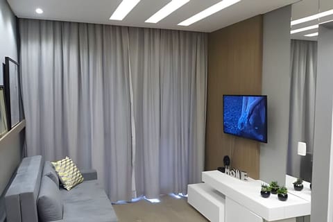 Living com TV, móveis planejados e varanda