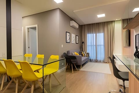 Sala espaçosa com ar condicionado, mesa de estudos/leitura, televisão, sofá 2 lugares e mesa 6 cadeiras.