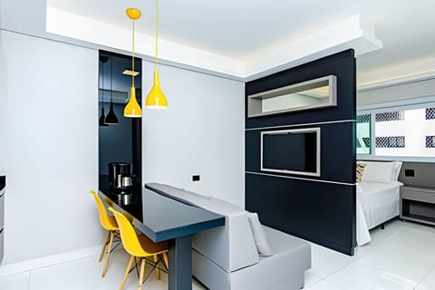 Sala com balcão 2 duas cadeiras para alimentação, sofá confortável e televisão de 40 pol.