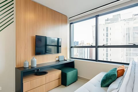 Sala com TV smart, painel de madeira e vista urbana pela janela