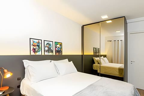 Quarto com cama de casal aconchegante, abajur e armário com espelho full body.