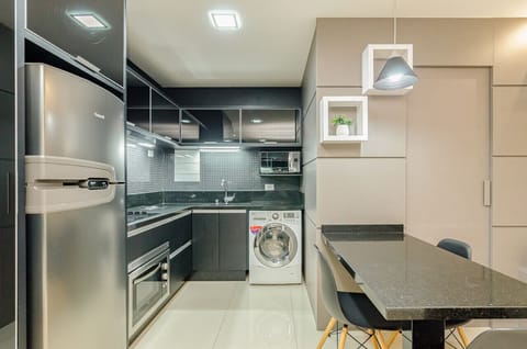 Cozinha moderna e completa com geladeira, forno, cooktop 4 bocas, exaustor, pia, armários, micro-ondas e lava e seca.