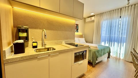 Studio completo com cozinha equipada, cama de casal e sacada com luz natural