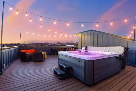 The hot tub and lounge seating on the rooftop, framed by string lights and city views, are where 24 people somehow feel like the right crew size