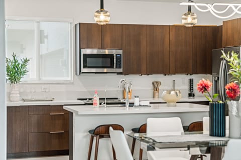 The kitchen features a stylish bar with three wooden seats