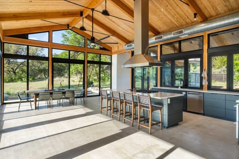 Chef's kitchen with bar seating and floor-to-ceiling windows-cook with a view and dine in nature's light.