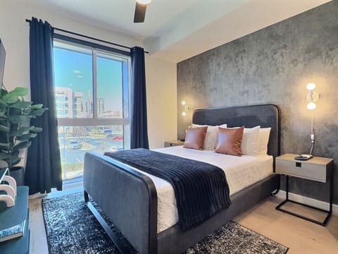 Relax in a cozy bedroom with city views inside a furnished apartment.