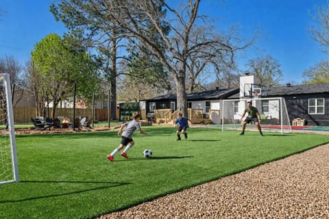 Large backyard turf field with soccer goals, fire pit, and room to play