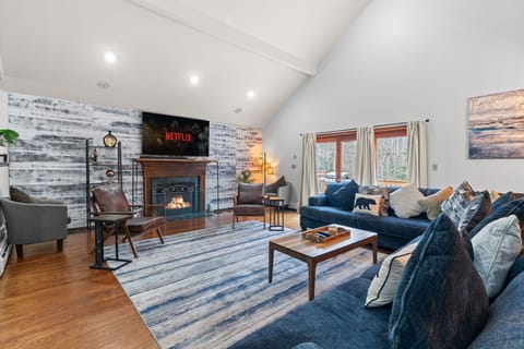 Bright open living room with vaulted ceilings, shiplap accent wall, and stone fireplace