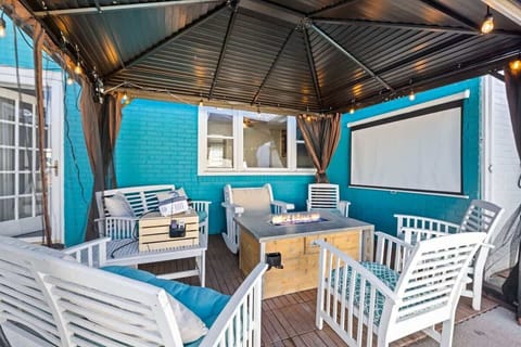 A covered outdoor patio with cushioned seating creates a peaceful retreat. The blue and white color palette adds a fresh coastal feel. 