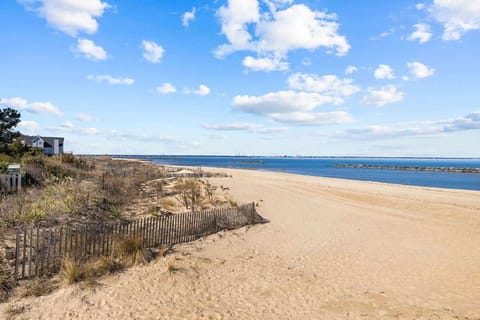 A sandy beach stretches into the horizon under a clear blue sky. This scenic spot is ideal for leisurely walks and ocean breezes.