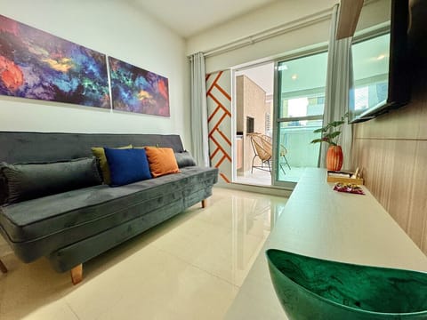 Sala de estar com sofa cinza, almofadas coloridas e vista para sacada