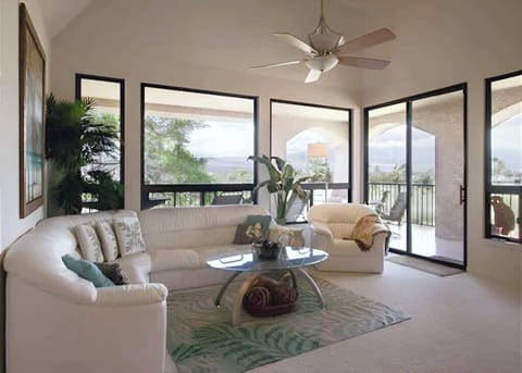 Bright and airy living room with panoramic views, plush white seating, and access to a breezy lanai.