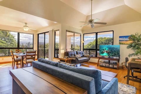 Spacious open living area with vaulted ceilings, large TV, dining space, and stunning tree top views.

