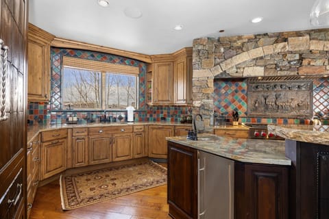 a gourmet kitchen with large island and ornate tile backsplash and a large chef's oven with a large window behind the sink