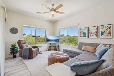 The Living Room is a bright space with plush seating, a Smart TV, and peaceful green views through large windows.