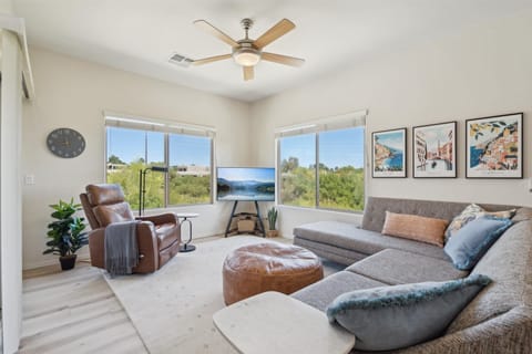 The Living Room is a bright space with plush seating, a Smart TV, and peaceful green views through large windows.