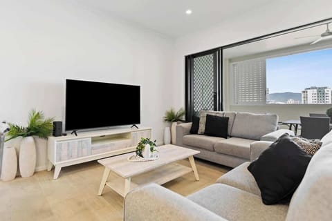 The light-filled living area offers two cosy sofas to settle in with a movie, while glass doors create a seamless flow out to the balcony. 