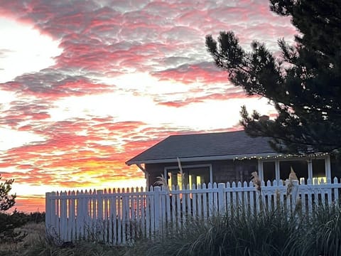 Sunset on the Pacific Ocean with guest house and fenced front yard. 