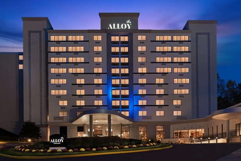 Tall building lit at night with glowing windows and Alloy sign