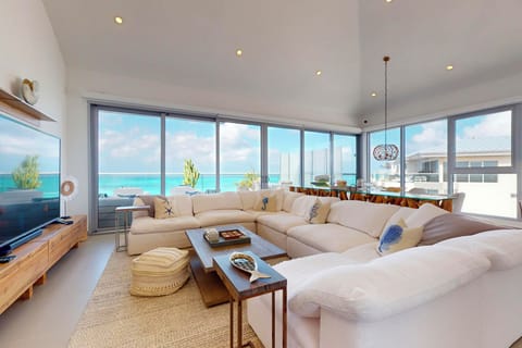 Sink into plush comfort as you gaze at turquoise waters through floor-to-ceiling windows. This spacious living room invites you to unwind with soft seating and coastal elegance.