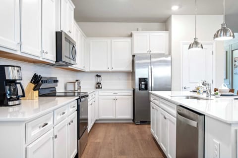 Fully equipped chef’s kitchen with white cabinetry, stainless steel, and ample space.
