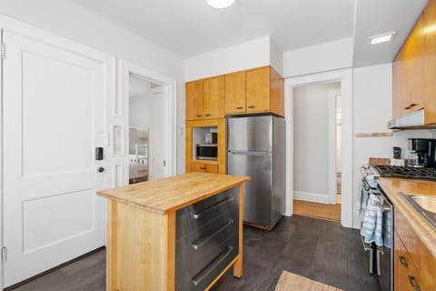 Your fully equipped kitchen awaits with warm wood cabinets, stainless steel appliances, and a charming island perfect for morning coffee or meal prep.