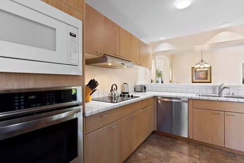 Cook with ease in this sleek kitchen featuring tiled counters, stainless appliances, and open sightlines.