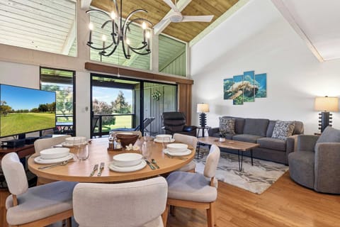 Spacious living area with vaulted wood ceilings, comfy seating, and beautiful tropical views outside.
Enjoy a meal with views of the golf course and open living space under vaulted wood ceilings.