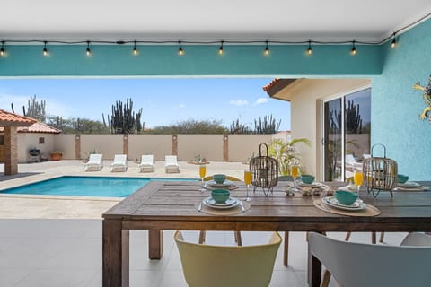Outdoor dining table with pool view Enjoy al fresco dining at your private outdoor table, overlooking the sparkling pool and lush garden. This cozy setup is perfect for family dinners under the Caribbean sky or a morning coffee before heading to Aruba’s b