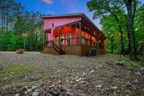 This charming red cabin nestled in the woods is your cozy escape complete with a welcoming front porch and twinkling lights that make you never want to leave.