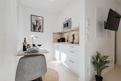 Eleganter Essbereich mit gemütlichen Stühlen, moderner Küchenzeile und Flachbild-TV – ideal für entspannte Abende.