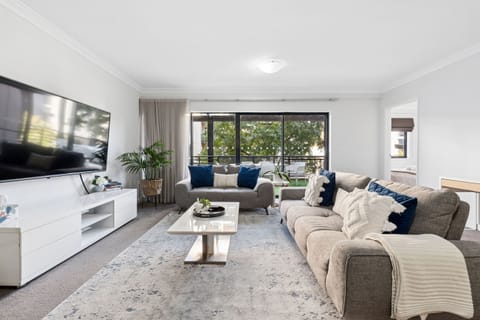 Unwind in the bright and airy living room featuring two large sofas, a sleek coffee table, and a smart TV. With stylish accents, plush cushions, and direct access to the balcony, it’s the perfect spot to relax or entertain.