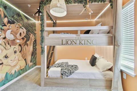 Step into a whimsical room designed for adventure, featuring a cozy bunk bed crafted from natural wood, with playful "Lion King" decor on the vibrant orange walls. Soft bedding invites restful nights after a day of exploration.