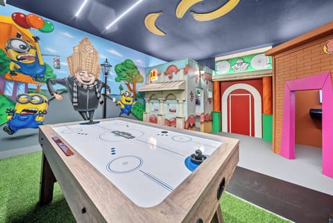 Step into a vibrant game room that sparks joy with its playful murals and colorful decor. The air hockey table takes center stage, set against a backdrop of whimsical characters, creating an exciting atmosphere for family fun.