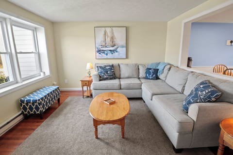 Coastal-style living room with comfy seating and 65" smart TV for streaming.