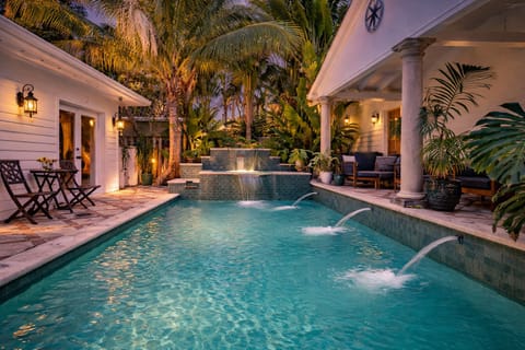 Beautiful pool area is surrounded by lush tropical greenery and offers various seating options for enjoying the tranquil setting.

